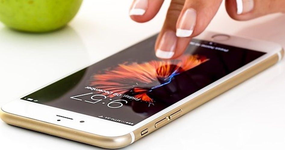 Image d'un portable et d'une main qui s'apprçete à toucher l'écran.
